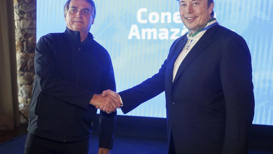 In this handout photo provided by the Ministry of Communication, Brazil's President Jair Bolsonaro, left, and Tesla and SpaceX chief executive officer Elon Musk shake hands during a meeting in Porto Feliz, Brazil, Friday, May 20, 2022. Musk met with Bolsonaro on Friday to discuss connectivity and other projects in the Amazon rainforest. (Cleverson Oliveira/Ministry of Communication via AP)