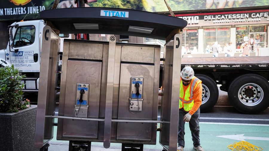 Seorang pekerja memindahkan telepon umum terakhir di dekat Times Square di New York City, AS, Senin (23/5/2022). (REUTERS/Brendan McDermid)