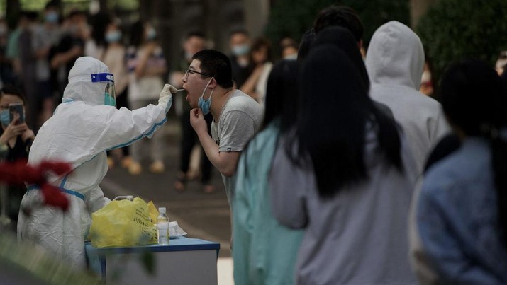 Seorang petugas kesehatan mengambil sampel swab dari seorang pria untuk diuji virus corona Covid-19 di tempat pengambilan swab di Beijing. (AFP/NOEL CELIS)