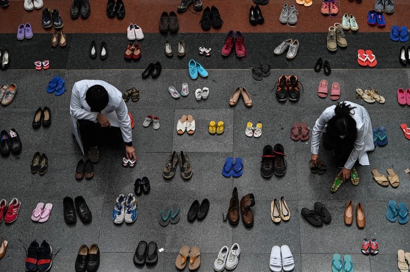 PHILIPPINES-HEALTH-TOBACCO A medical staff stands in between pairs of shoes, part of an art installation with 321 pairs of shoes that signifies the deaths caused by smoking, in observance to the World No Tobacco Day, at the Lung Center of the Philippines in Quezon City, suburban Manila on May 31, 2022. (Photo by JAM STA ROSA / AFP)