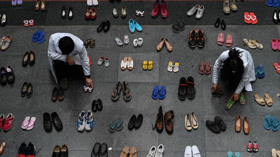 A medical staff stands in between pairs of shoes, part of an art installation with 321 pairs of shoes that signifies the deaths caused by smoking, in observance to the World No Tobacco Day, at the Lung Center of the Philippines in Quezon City, suburban Manila on May 31, 2022. (Photo by JAM STA ROSA / AFP)