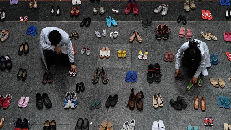A medical staff stands in between pairs of shoes, part of an art installation with 321 pairs of shoes that signifies the deaths caused by smoking, in observance to the World No Tobacco Day, at the Lung Center of the Philippines in Quezon City, suburban Manila on May 31, 2022. (Photo by JAM STA ROSA / AFP)