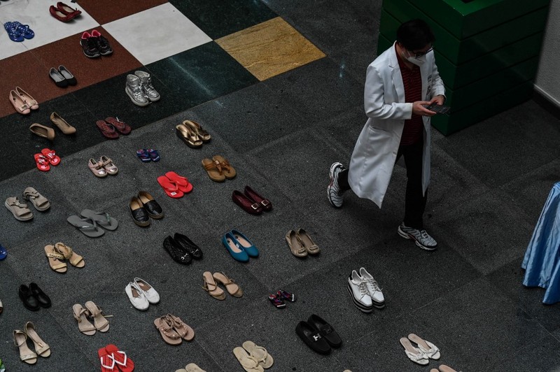 A medical staff stands in between pairs of shoes, part of an art installation with 321 pairs of shoes that signifies the deaths caused by smoking, in observance to the World No Tobacco Day, at the Lung Center of the Philippines in Quezon City, suburban Manila on May 31, 2022. (Photo by JAM STA ROSA / AFP)