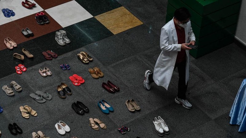 A medical staff stands in between pairs of shoes, part of an art installation with 321 pairs of shoes that signifies the deaths caused by smoking, in observance to the World No Tobacco Day, at the Lung Center of the Philippines in Quezon City, suburban Manila on May 31, 2022. (Photo by JAM STA ROSA / AFP)