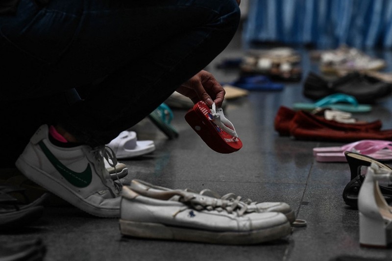 PHILIPPINES-HEALTH-TOBACCO A medical staff stands in between pairs of shoes, part of an art installation with 321 pairs of shoes that signifies the deaths caused by smoking, in observance to the World No Tobacco Day, at the Lung Center of the Philippines in Quezon City, suburban Manila on May 31, 2022. (Photo by JAM STA ROSA / AFP)