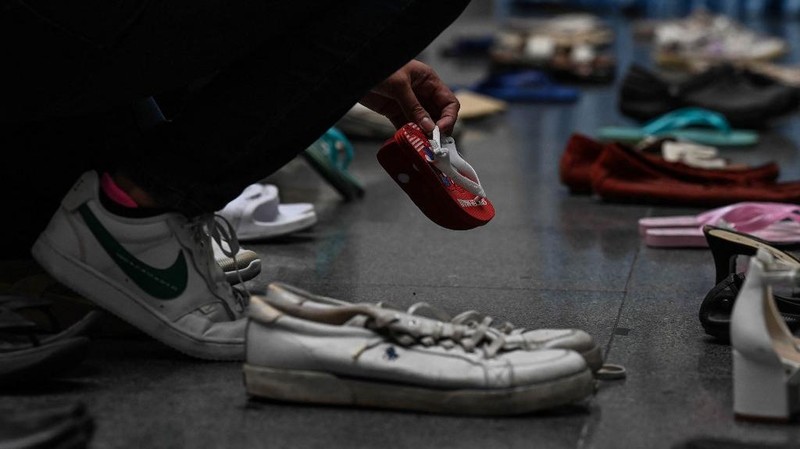 A medical staff stands in between pairs of shoes, part of an art installation with 321 pairs of shoes that signifies the deaths caused by smoking, in observance to the World No Tobacco Day, at the Lung Center of the Philippines in Quezon City, suburban Manila on May 31, 2022. (Photo by JAM STA ROSA / AFP)