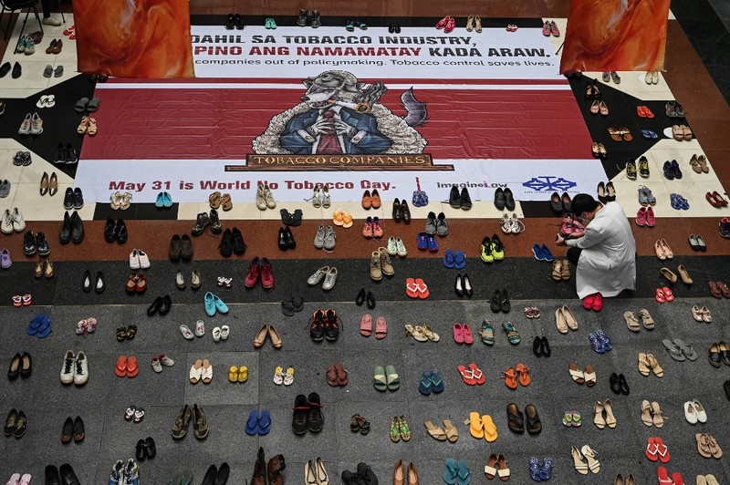 PHILIPPINES-HEALTH-TOBACCO A medical staff stands in between pairs of shoes, part of an art installation with 321 pairs of shoes that signifies the deaths caused by smoking, in observance to the World No Tobacco Day, at the Lung Center of the Philippines in Quezon City, suburban Manila on May 31, 2022. (Photo by JAM STA ROSA / AFP)