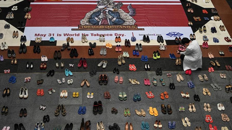 A medical staff stands in between pairs of shoes, part of an art installation with 321 pairs of shoes that signifies the deaths caused by smoking, in observance to the World No Tobacco Day, at the Lung Center of the Philippines in Quezon City, suburban Manila on May 31, 2022. (Photo by JAM STA ROSA / AFP)