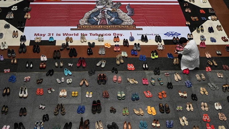 A medical staff stands in between pairs of shoes, part of an art installation with 321 pairs of shoes that signifies the deaths caused by smoking, in observance to the World No Tobacco Day, at the Lung Center of the Philippines in Quezon City, suburban Manila on May 31, 2022. (Photo by JAM STA ROSA / AFP)