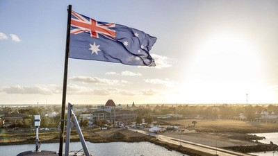 This handout photo taken on January 26, 2022 by the Australian Defence Force shows the Australian flag flying on board the HMAS Adelaide as the ship arrives in Nuku'alofa, Tonga, carrying disaster relief and humanitarian aid supplies following the January 15 eruption of the Hunga Tonga-Hunga Haapai underwater volcano nearby. (Photo by CPL Robert Whitmore / Australian Defence Force / AFP) / -----EDITORS NOTE --- RESTRICTED TO EDITORIAL USE - MANDATORY CREDIT 