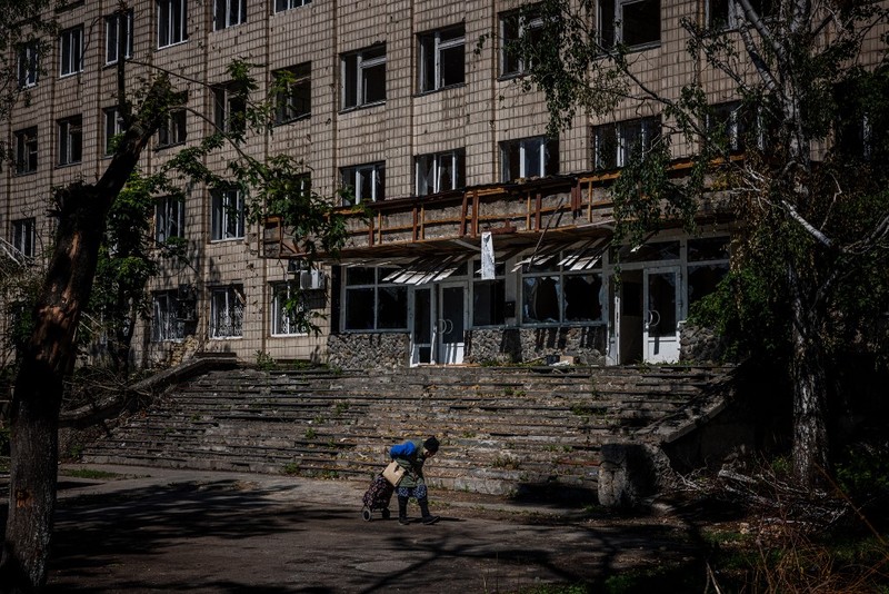 Kota Hancur Serangan rusia ke ukraina di kota Slovyansk di wilayah Donbas, Ukraina timur Seorang gadis berjalan di depan gedung apartemen yang rusak setelah serangan Rusia ke Ukraina di kota Slovyansk di wilayah Donbas, Ukraina timur, Selasa (31/5/2022). (Photo by ARIS MESSINIS / AFP)