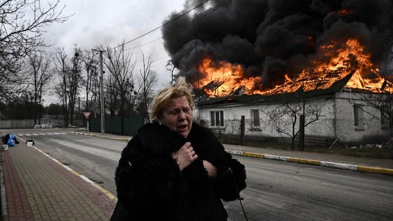 Seorang gadis berjalan di depan gedung apartemen yang rusak setelah serangan Rusia ke Ukraina di kota Slovyansk di wilayah Donbas, Ukraina timur, Selasa (31/5/2022). (Photo by ARIS MESSINIS / AFP)