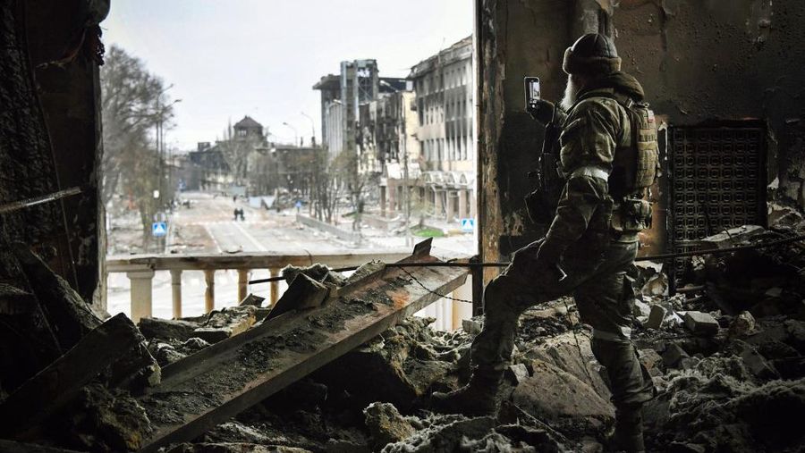 Seorang tentara Rusia berpatroli di teater drama Mariupol yang dibom 16 Maret lalu di Mariupol, Selasa (12/4/2022). (Photo by Alexander NEMENOV / AFP)