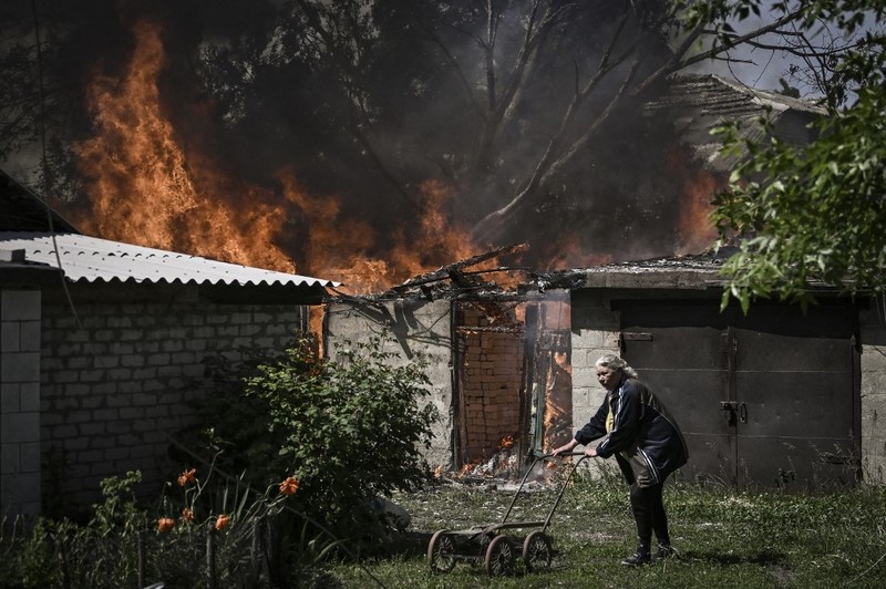 Seorang gadis berjalan di depan gedung apartemen yang rusak setelah serangan Rusia ke Ukraina di kota Slovyansk di wilayah Donbas, Ukraina timur, Selasa (31/5/2022). (Photo by ARIS MESSINIS / AFP)