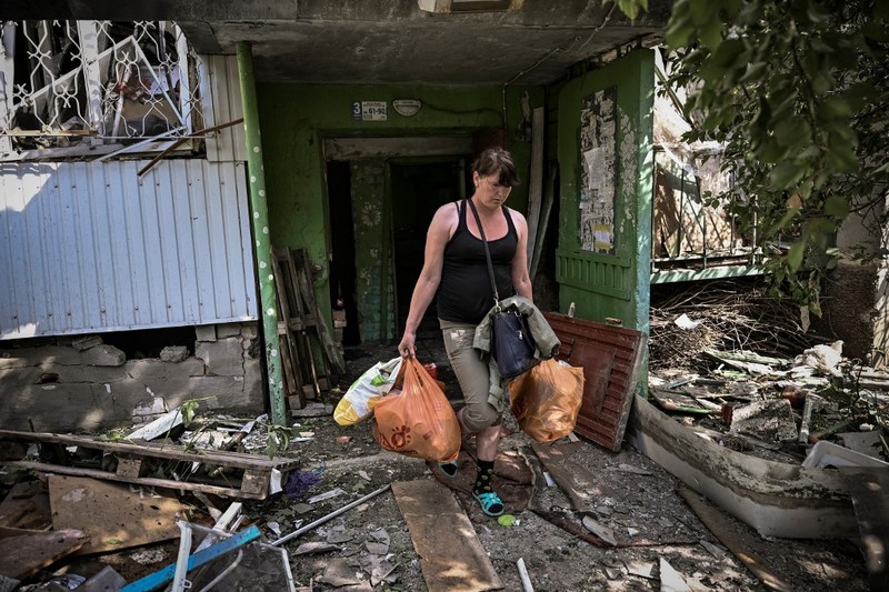 Kota Hancur Serangan rusia ke ukraina di kota Slovyansk di wilayah Donbas, Ukraina timur Seorang gadis berjalan di depan gedung apartemen yang rusak setelah serangan Rusia ke Ukraina di kota Slovyansk di wilayah Donbas, Ukraina timur, Selasa (31/5/2022). (Photo by ARIS MESSINIS / AFP)