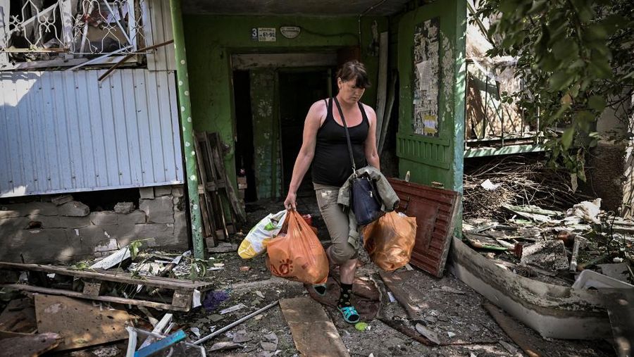 Seorang gadis berjalan di depan gedung apartemen yang rusak setelah serangan Rusia ke Ukraina di kota Slovyansk di wilayah Donbas, Ukraina timur, Selasa (31/5/2022). (Photo by ARIS MESSINIS / AFP)