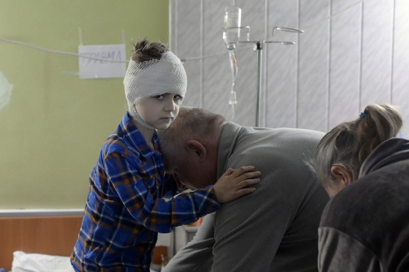 TOPSHOT - People standing near a Ukrainian national flag watch as dark smoke billows following an air strike in the western Ukrainian city of Lviv, on March 26, 2022. - At least five people wounded in two strikes on Lviv, the regional governor said, in a rare attack on a city that has escaped serious fighting since Russian troops invaded last month. (Photo by Aleksey Filippov / AFP) (Photo by ALEKSEY FILIPPOV/AFP via Getty Images)