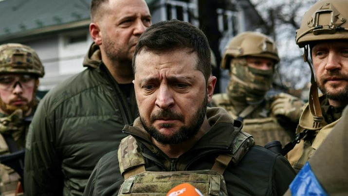 TOPSHOT - Ukrainian President Volodymyr Zelensky (C) speaks to media in the town of Bucha, northwest of the Ukrainian capital Kyiv, on April 4, 2022. - Ukraine's President Volodymyr Zelensky said on April 3, 2022 the Russian leadership was responsible for civilian killings in Bucha, outside Kyiv, where bodies were found lying in the street after the town was retaken by the Ukrainian army. (Photo by RONALDO SCHEMIDT / AFP) (Photo by RONALDO SCHEMIDT/AFP via Getty Images)