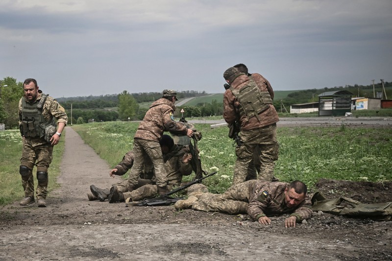 1239523382 TOPSHOT - People standing near a Ukrainian national flag watch as dark smoke billows following an air strike in the western Ukrainian city of Lviv, on March 26, 2022. - At least five people wounded in two strikes on Lviv, the regional governor said, in a rare attack on a city that has escaped serious fighting since Russian troops invaded last month. (Photo by Aleksey Filippov / AFP) (Photo by ALEKSEY FILIPPOV/AFP via Getty Images)