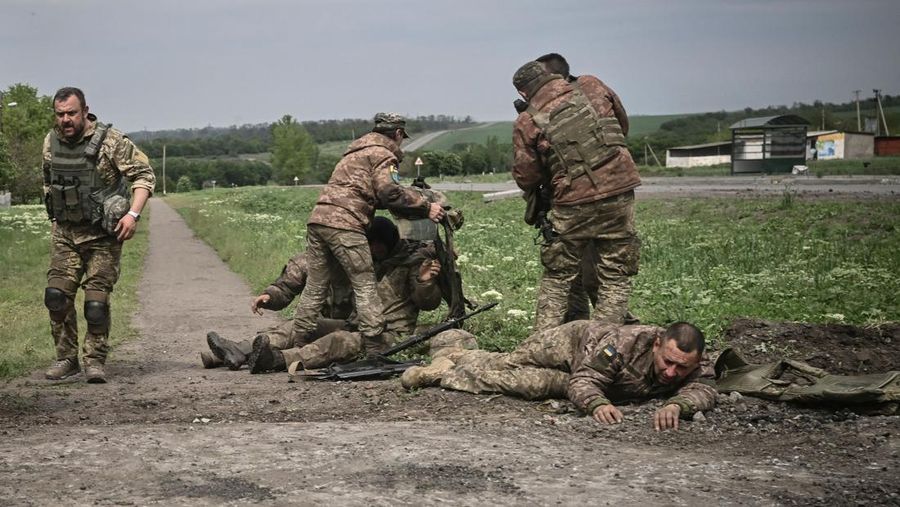 TOPSHOT - Ukrainian servicemen assist their comrades not far from the frontline in the eastern Ukrainian region of Donbas, on May 21, 2022. (Photo by AFP) (Photo by -/AFP via Getty Images)