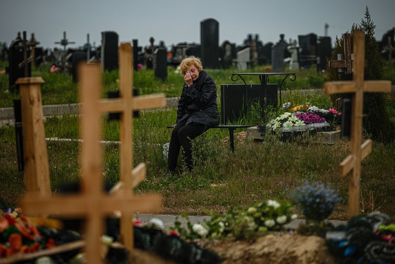1239523382 TOPSHOT - People standing near a Ukrainian national flag watch as dark smoke billows following an air strike in the western Ukrainian city of Lviv, on March 26, 2022. - At least five people wounded in two strikes on Lviv, the regional governor said, in a rare attack on a city that has escaped serious fighting since Russian troops invaded last month. (Photo by Aleksey Filippov / AFP) (Photo by ALEKSEY FILIPPOV/AFP via Getty Images)