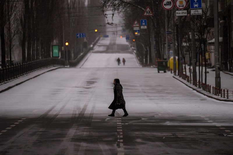 1239523382 TOPSHOT - People standing near a Ukrainian national flag watch as dark smoke billows following an air strike in the western Ukrainian city of Lviv, on March 26, 2022. - At least five people wounded in two strikes on Lviv, the regional governor said, in a rare attack on a city that has escaped serious fighting since Russian troops invaded last month. (Photo by Aleksey Filippov / AFP) (Photo by ALEKSEY FILIPPOV/AFP via Getty Images)