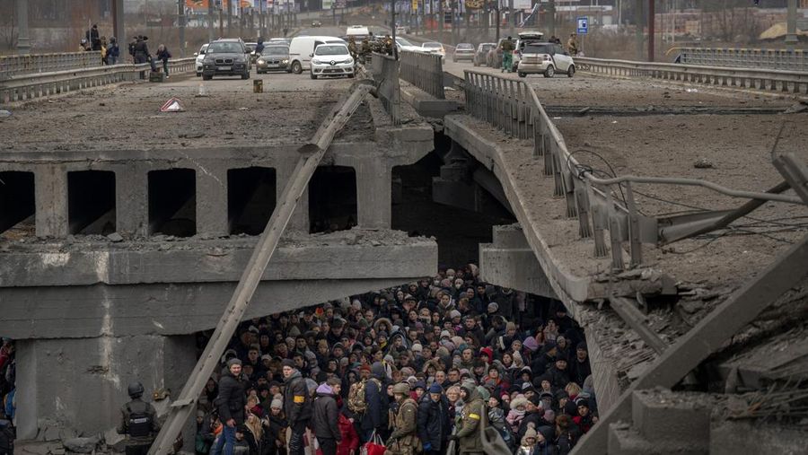 Ukrainians crowd under a destroyed bridge as they try to flee by crossing the Irpin River on the outskirts of Kyiv, Ukraine, Saturday, March 5, 2022. (AP Photo/Emilio Morenatti)