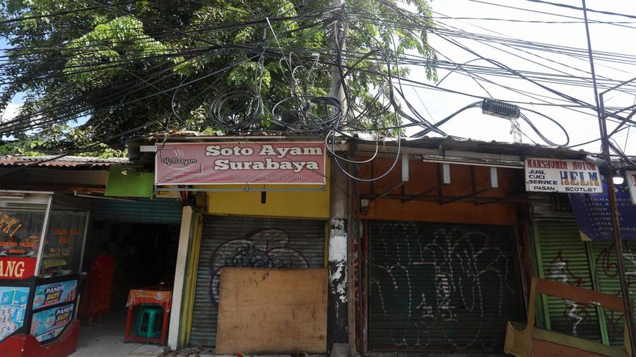 Kendaraan melintas di samping kabel yang semrawut di kawasan jalan Raya Pd. Gede, Pinang Ranti, Jakarta Timur, Jumat (3/6/2022). (CNBC Indonesia/ Andrean Kristianto)