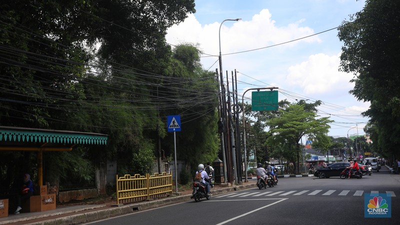 Kendaraan melintas di samping kabel yang semrawut di kawasan jalan Raya Pd. Gede, Pinang Ranti, Jakarta Timur, Jumat (3/6/2022). (CNBC Indonesia/ Andrean Kristianto)