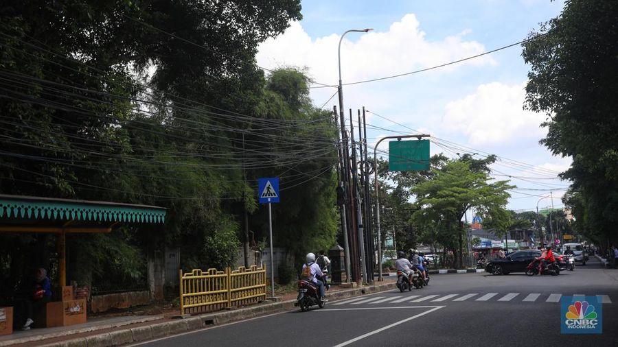 Kendaraan melintas di samping kabel yang semrawut di kawasan jalan Raya Pd. Gede, Pinang Ranti, Jakarta Timur, Jumat (3/6/2022). (CNBC Indonesia/ Andrean Kristianto)