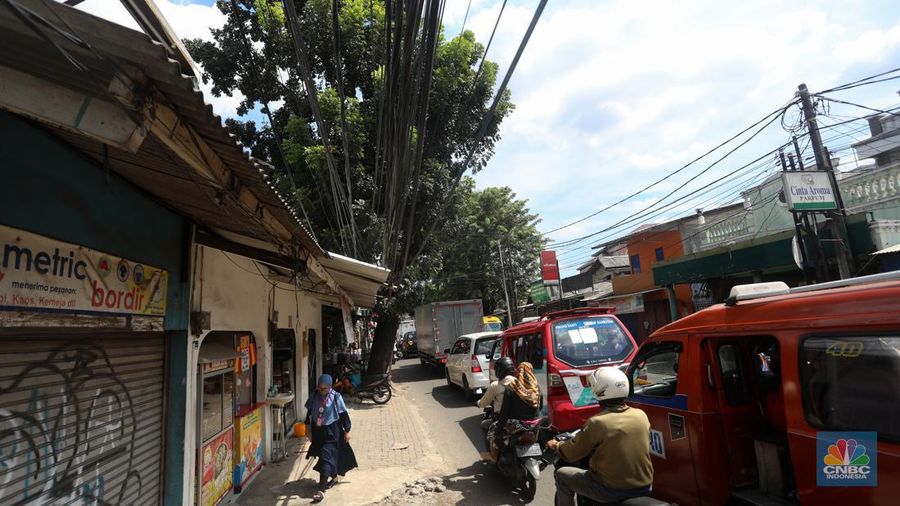 Kendaraan melintas di samping kabel yang semrawut di kawasan jalan Raya Pd. Gede, Pinang Ranti, Jakarta Timur, Jumat (3/6/2022). (CNBC Indonesia/ Andrean Kristianto)