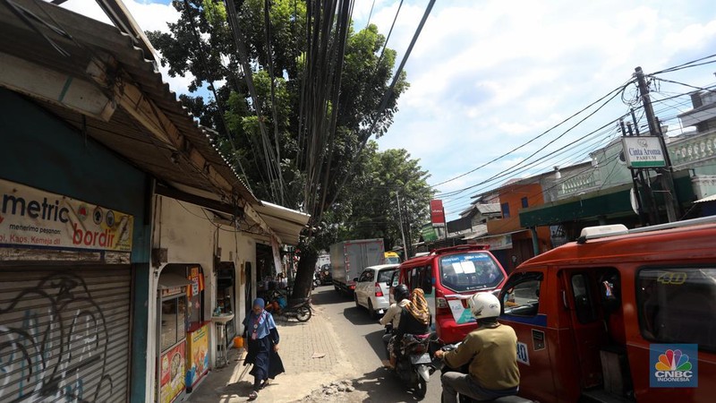 Kendaraan melintas di samping kabel yang semrawut di kawasan jalan Raya Pd. Gede, Pinang Ranti, Jakarta Timur, Jumat (3/6/2022). (CNBC Indonesia/ Andrean Kristianto)