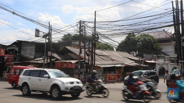 Kendaraan melintas di samping kabel yang semrawut di kawasan jalan Raya Pd. Gede, Pinang Ranti, Jakarta Timur, Jumat (3/6/2022). (CNBC Indonesia/ Andrean Kristianto)