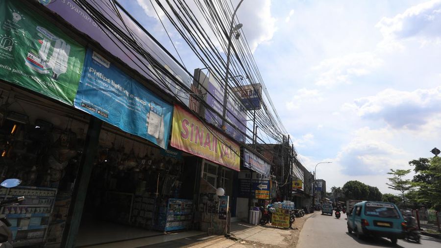 Kendaraan melintas di samping kabel yang semrawut di kawasan jalan Raya Pd. Gede, Pinang Ranti, Jakarta Timur, Jumat (3/6/2022). (CNBC Indonesia/ Andrean Kristianto)