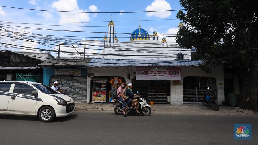 Kendaraan melintas di samping kabel yang semrawut di kawasan jalan Raya Pd. Gede, Pinang Ranti, Jakarta Timur, Jumat (3/6/2022). (CNBC Indonesia/ Andrean Kristianto)