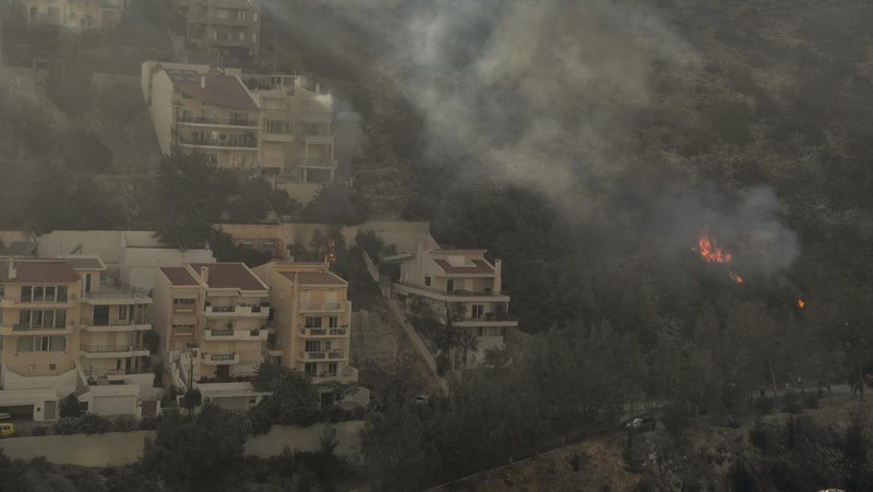 Petugas pemadam kebakaran berusaha memadamkan api dari daerah pemukiman di Panorama Voulas, selatan Athena, Yunani, Sabtu (4/6/2022). Lebih dari 130 petugas pemadam kebakaran dibantu 6 pesawat pemadam kebakaran dan 4 helikopter menjatuhkan berton-ton air untuk memadamkan kebakaran hutan yang dipicu oleh angin kencang tersebut. (Photo by Louisa GOULIAMAKI / AFP)