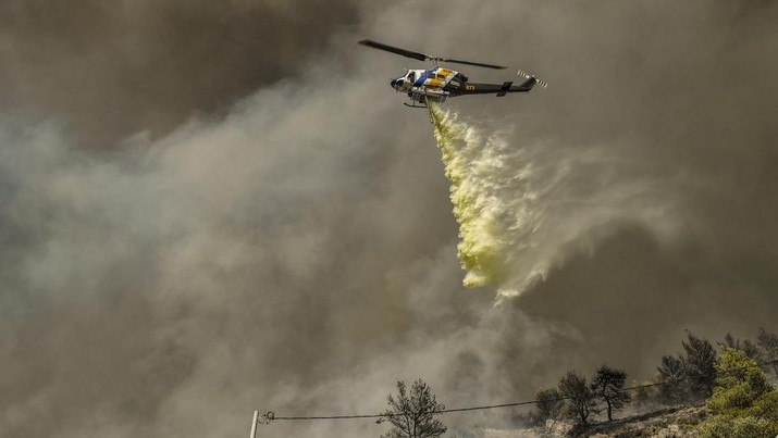 Kebakaran Hutan di Panorama Voulas, selatan Athena, Yunani Sebuah helikopter menjatuhkan air di atas kebakaran hutan di pinggiran kota Voula, Athena selatan, Yunani, Sabtu (4/6/2022). Lebih dari 130 petugas pemadam kebakaran dibantu 6 pesawat pemadam kebakaran dan 4 helikopter menjatuhkan berton-ton air untuk memadamkan kebakaran hutan yang dipicu oleh angin kencang tersebut. (Photo by Milos Bicanski/Getty Images)