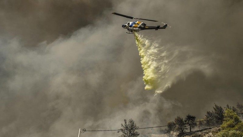 Petugas pemadam kebakaran berusaha memadamkan api dari daerah pemukiman di Panorama Voulas, selatan Athena, Yunani, Sabtu (4/6/2022). Lebih dari 130 petugas pemadam kebakaran dibantu 6 pesawat pemadam kebakaran dan 4 helikopter menjatuhkan berton-ton air untuk memadamkan kebakaran hutan yang dipicu oleh angin kencang tersebut. (Photo by Louisa GOULIAMAKI / AFP)