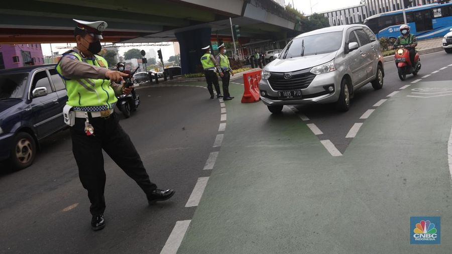 Sejumlah polisi lalulintas memberhentikan pengendara mobil yang melanggar peraturan lalu lintas saat pemberlakuan aturan ganjil genap di kawasan Kramat Raya, Jakarta, Senin (6/6/2022). (CNBC Indonesia/Andrean Kristianto)