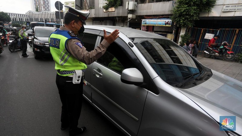Sejumlah polisi lalulintas memberhentikan pengendara mobil yang melanggar peraturan lalu lintas saat pemberlakuan aturan ganjil genap di kawasan Kramat Raya, Jakarta, Senin (6/6/2022). (CNBC Indonesia/Andrean Kristianto)
