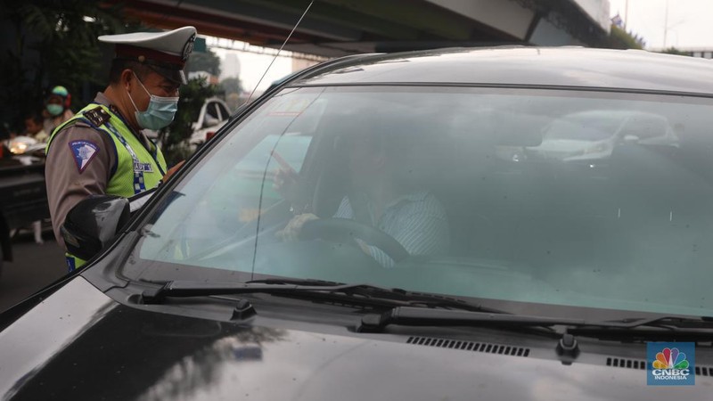 Sejumlah polisi lalulintas memberhentikan pengendara mobil yang melanggar peraturan lalu lintas saat pemberlakuan aturan ganjil genap di kawasan Kramat Raya, Jakarta, Senin (6/6/2022). (CNBC Indonesia/Andrean Kristianto)