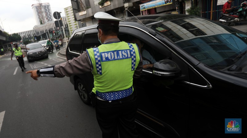 Sejumlah polisi lalulintas memberhentikan pengendara mobil yang melanggar peraturan lalu lintas saat pemberlakuan aturan ganjil genap di kawasan Kramat Raya, Jakarta, Senin (6/6/2022). (CNBC Indonesia/Andrean Kristianto)