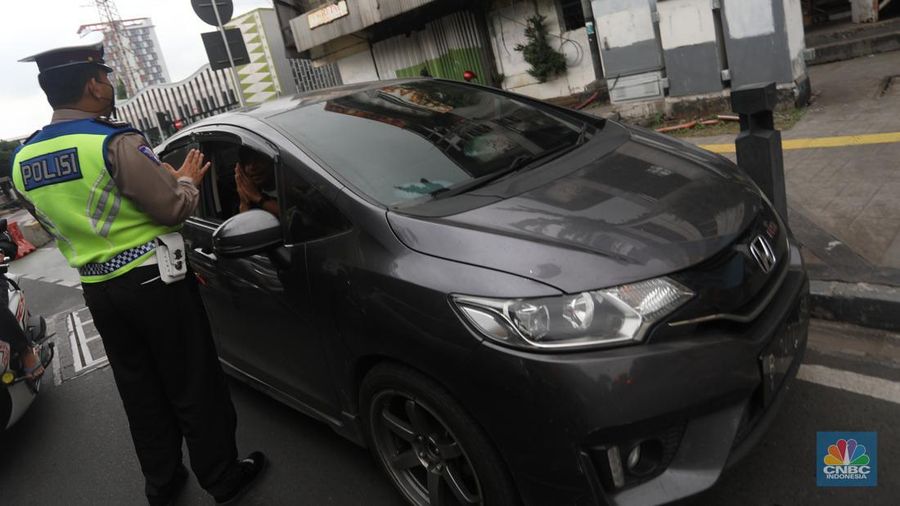 Sejumlah polisi lalulintas memberhentikan pengendara mobil yang melanggar peraturan lalu lintas saat pemberlakuan aturan ganjil genap di kawasan Kramat Raya, Jakarta, Senin (6/6/2022). (CNBC Indonesia/Andrean Kristianto)