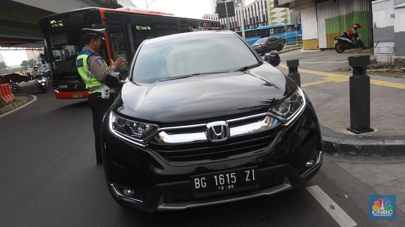 Sejumlah polisi lalulintas memberhentikan pengendara mobil yang melanggar peraturan lalu lintas saat pemberlakuan aturan ganjil genap di kawasan Kramat Raya, Jakarta, Senin (6/6/2022). (CNBC Indonesia/Andrean Kristianto)