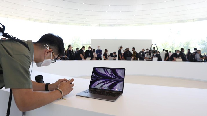 Seorang peserta mengambil gambar laptop MacBook Air yang baru didesain ulang selama WWDC22 di Apple Park pada 06 Juni 2022 di Cupertino, California. CEO Apple Tim Cook memulai konferensi pengembang tahunan WWDC22. (Getty Images/Justin Sullivan)
