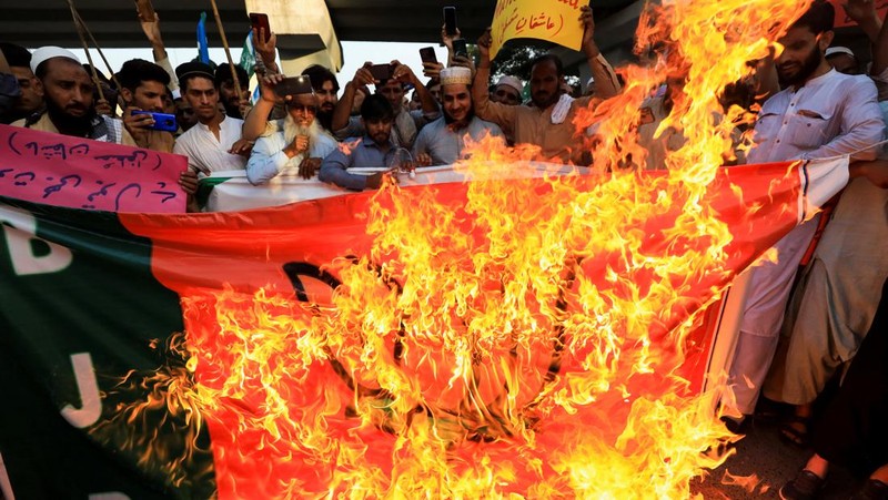 Pendukung kelompok agama Tehreek-e-Hurmat-e-Rasool membakar representasi bendera India selama demonstrasi untuk mengutuk referensi menghina Islam dan Nabi Muhammad yang dibuat baru-baru ini oleh Nupur Sharma, juru bicara partai nasionalis Hindu India yang memerintah di Lahore, Pakistan. (AP/K.M. Chaudary)
