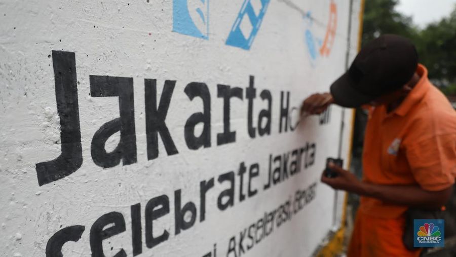 Petugas Penanganan Prasarana dan Sarana (PPSU) mengecat tembok di sepanjang jalan raya I Gusti Ngurah Rai, Jakarta, Kamis, (9/6/2022). (CNBC Indonesia/Muhammad Sabki)
