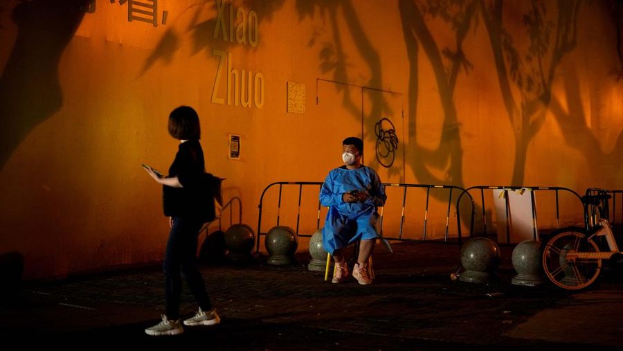 Seorang pekerja dengan pakaian pelindung berjaga-jaga di area jalan, setelah penguncian yang dilakukan untuk mengekang wabah penyakit coronavirus (COVID-19) dicabut di Shanghai, Cina. (REUTERS/ALY SONG)