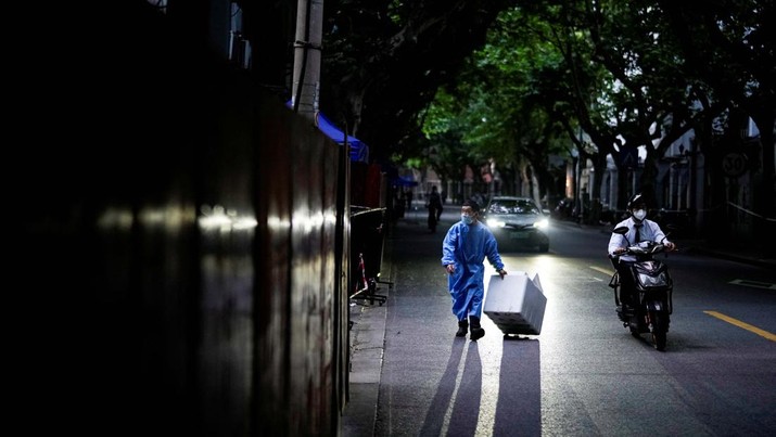 Seorang pekerja dengan pakaian pelindung membawa kotak styrofoam di jalan, setelah penguncian yang dilakukan untuk mengekang wabah penyakit coronavirus (COVID-19) dicabut di Shanghai, Cina. (REUTERS/ALY SONG)