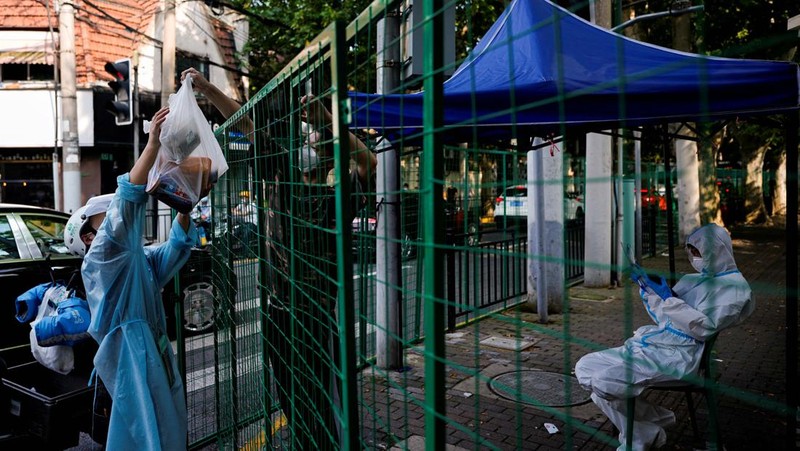 Warga mengenakan masker pelindung berbicara dengan petugas keamanan dan pekerja dengan pakaian pelindung di area berpagar di mana pembatasan untuk mengekang penyakit virus corona (COVID-19) diberlakukan, di Shanghai, Cina 6 Juni 2022. (REUTERS/ALY SONG)